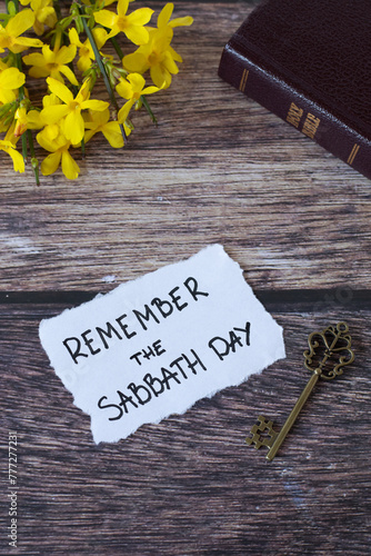 Remember the Sabbath Day, handwritten note with holy bible, antique key, and flowers on wooden table. Christian obedience, keeping the commandments, rest for the people of God, biblical concept.