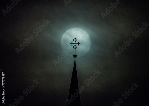 mistyczny obraz księżyca w pełni i krzyża na wieży kościoła w nocy we mgle