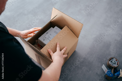 Ein Arbeiter verpackt ein Paket, verschließt es mit Klebeband, macht fertig zum Versand