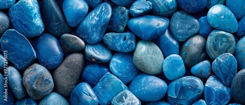 Captivating assortment of polished blue stones in diverse shades and shapes, forming a visually striking and hypnotizing natural landscape.