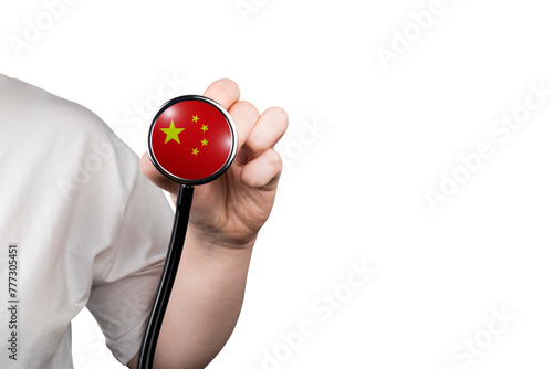 The head of a medical stethoscope in the form of the Chinese flag in a hand (close-up) on a transparent background. Chinese medicine concept