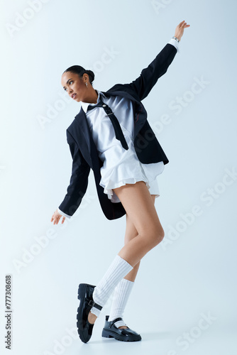 Young African American woman wearing a suit and tie, dancing in a studio. photo