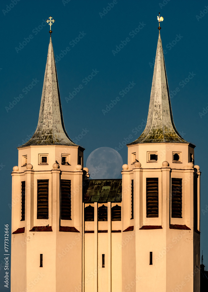 księżyc w pełni zachodzący za dwoma wieżami kościoła - obrazy, fototapety, plakaty 