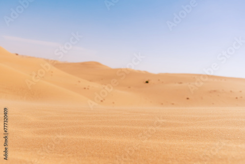 Wide desert sand dune with hills and blue sky. Grained yellow sand. Abstract landscape backgrounds