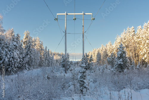 Power lines cross the countryside in a snowy and sunny sweden