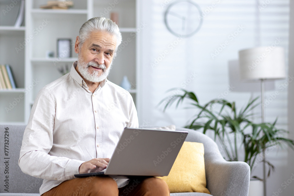 Senior man working on laptop in a bright living room Senior man working on laptop in a bright living room