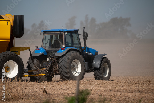 Tractor azul que traslada maquinaria en campo argentino