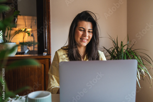 One young girl or woman is using her laptop to work from home in the morning while drinking coffee