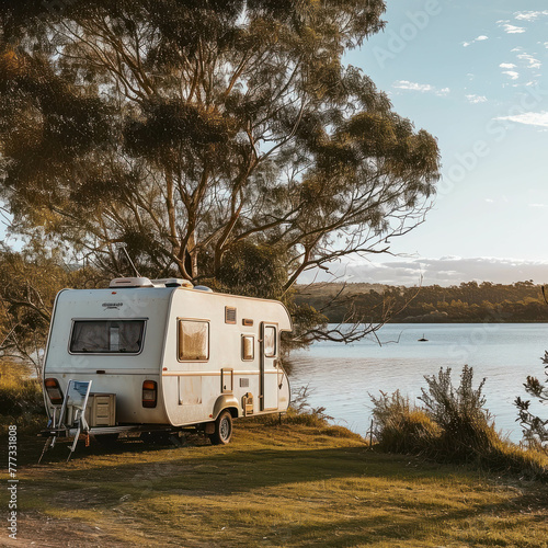 Explore outdoor adventure with a camper trailer parked by a lake in the grassy countryside. Enjoy the peaceful getaway amidst nature's beauty. AI generative enriches the scenic view.