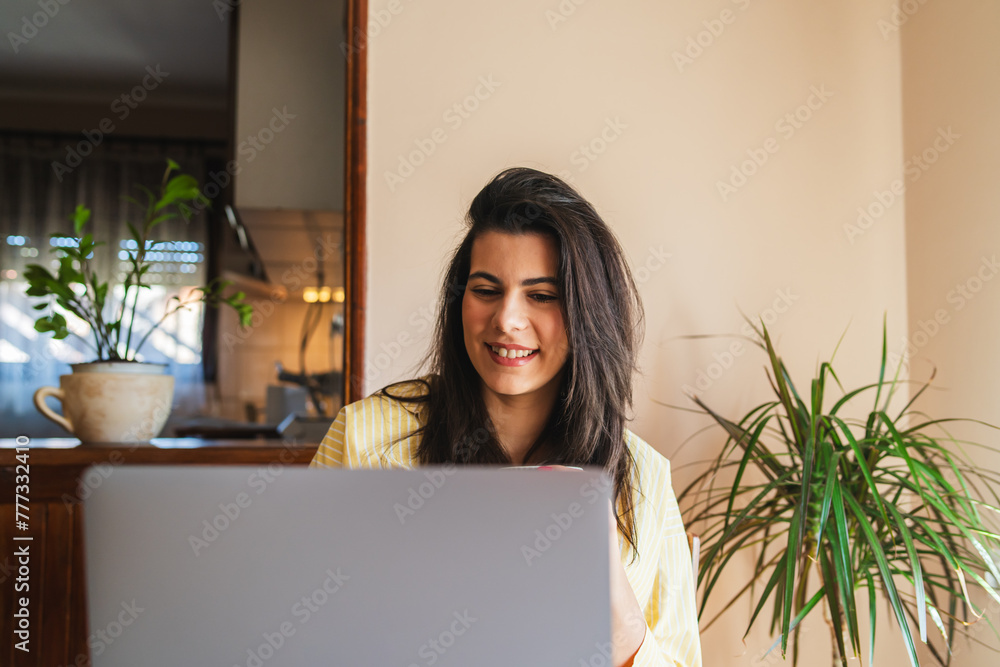 One young girl or woman is using her laptop to work from home in the morning while drinking coffee One young girl or woman is using her laptop to work from home in the morning while drinking coffee
