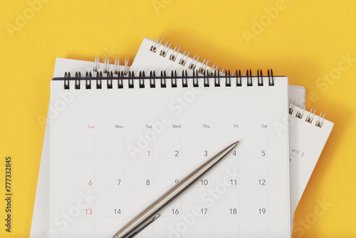 A pen with calendar on yellow background.