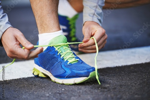 Foot, runner and tying laces on street in outdoors, cardio and exercise or training for marathon. Person, athlete and ready for workout in closeup, sportswear and performance challenge on asphalt