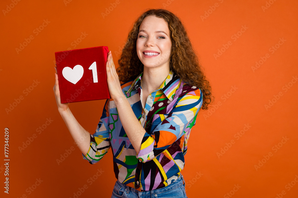 Photo of lovely adorable girl wear stylish print clothes hands hold red heart symbol isolated on vivid orange color background