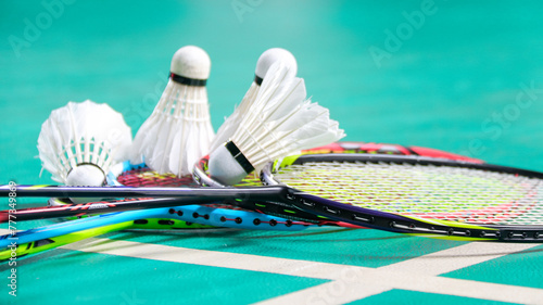 White badminton shuttlecocks and badminton rackets on green floor indoor badminton court soft and selective focus on shuttlecocks and the rackets