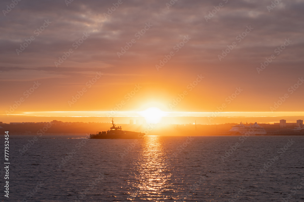 A military boat approaches Tallinn at dawn.