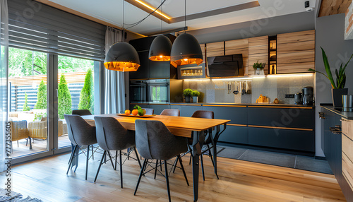 Interior of modern open plan kitchen with dining table and glowing lamps