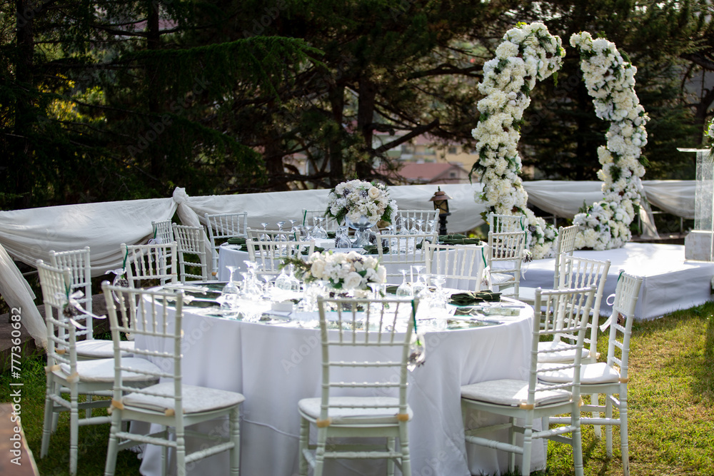 White color wedding table decorated with decorative and elegant for wedding. There are flowers, candles and serving plates on the wedding table.