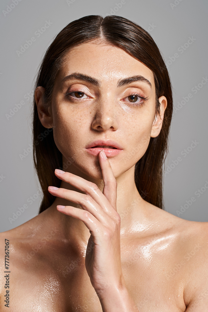 A young Caucasian woman with brunette hair posing confidently without a shirt in a studio setting. A young Caucasian woman with brunette hair posing confidently without a shirt in a studio setting.