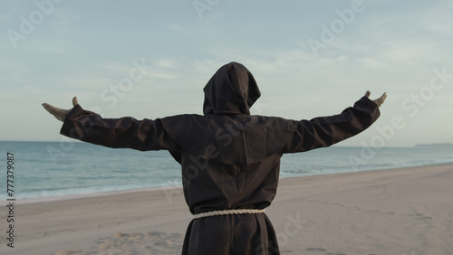 Religious Monk With Prays Towards The Sea With Open Arms