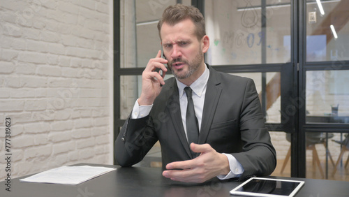 Angry Middle Aged Businessman Talking on Phone