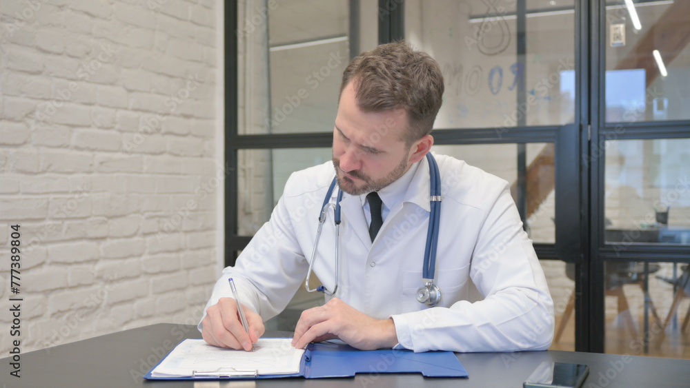 Fototapeta premium Middle Aged Doctor Working on Documents in Clinic
