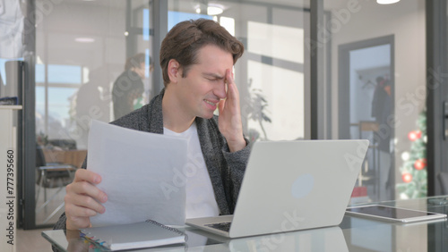 Young Man Feeling Upset while Reading Contract at Work