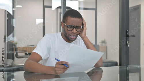 Young African Man Feeling Upset while Reading Contract