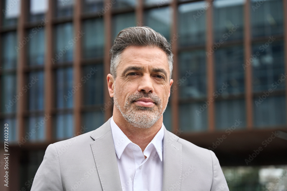 Portrait of confident rich 45 years old middle aged man business owner, mature company ceo executive, Latin investor wearing suit standing outside office on city street looking at camera. Headshot Portrait of confident rich 45 years old middle aged man business owner, mature company ceo executive, Latin investor wearing suit standing outside office on city street looking at camera. Headshot