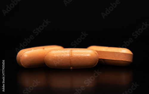 close up of three pills on a black background