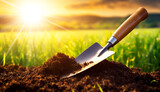 Closeup and bottom view of soil with a garden trowel and green grass on background at sunset or sunrise, gardening or agriculture concept. Generative Ai.