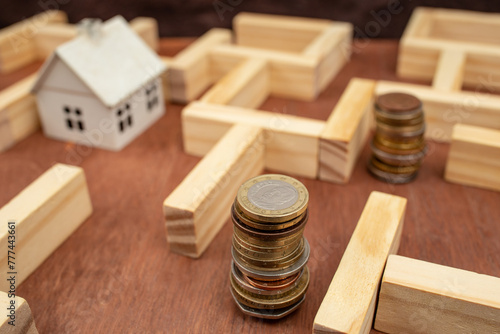 Coin stacks and a miniature white house in a wooden maze, economic difficulties metaphor, soft focus close up