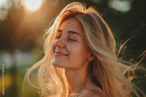 Young woman eyes closed enjoying sunset in park