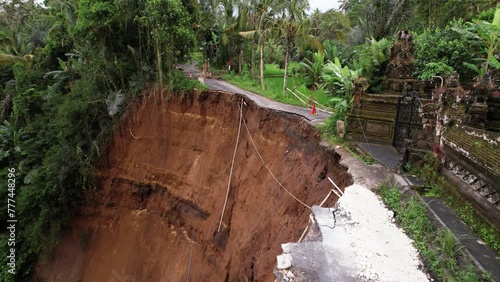 A unique aerial perspective of results of dangerous landslide. Road broken, unstable ground fall down to ravine, buildings in high risk. Small earthquake and heavy rains aftermath at central Bali photo