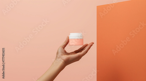 Mockup of jar for beauty crem. Womans hand holding a jar of cream. Concept for cosmetics. Peach color background. Space for text.