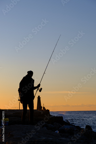 A man standing and fishing at the Kyrenia Harbour at the blue hour in Cyprus