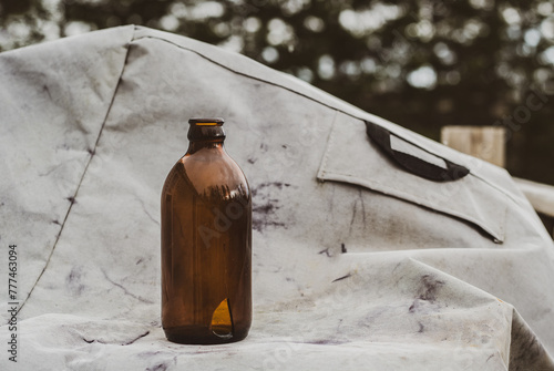Cuadro en lienzo Old stubby beer bottle on barbecue cover