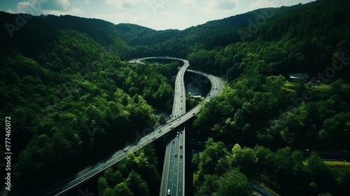 Aerial view of highway and bridge surrounded by lush green forest on a bright summer day
