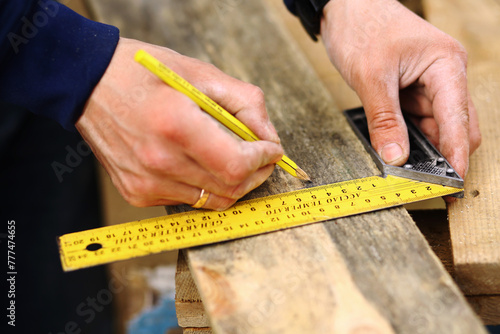Close up photo of carpenter craftsman trace the cutting line on a wooden board with a pencil and the carpenter's square