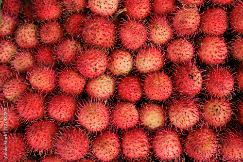 A close up of many red ramboutans in a Thai market. photo