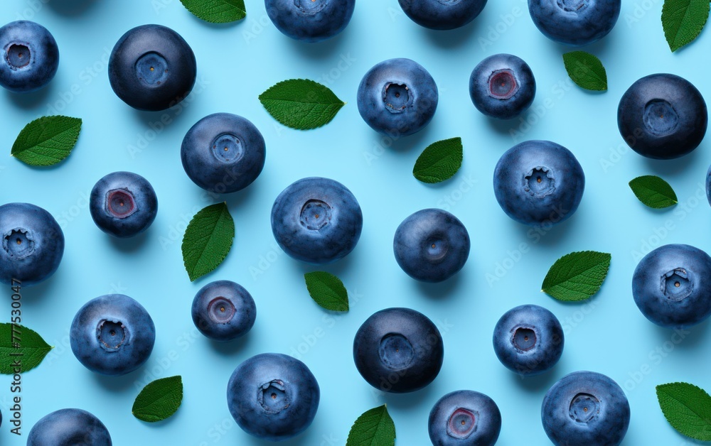 Pattern of blueberries with leaves on blue backdrop Pattern of blueberries with leaves on blue backdrop