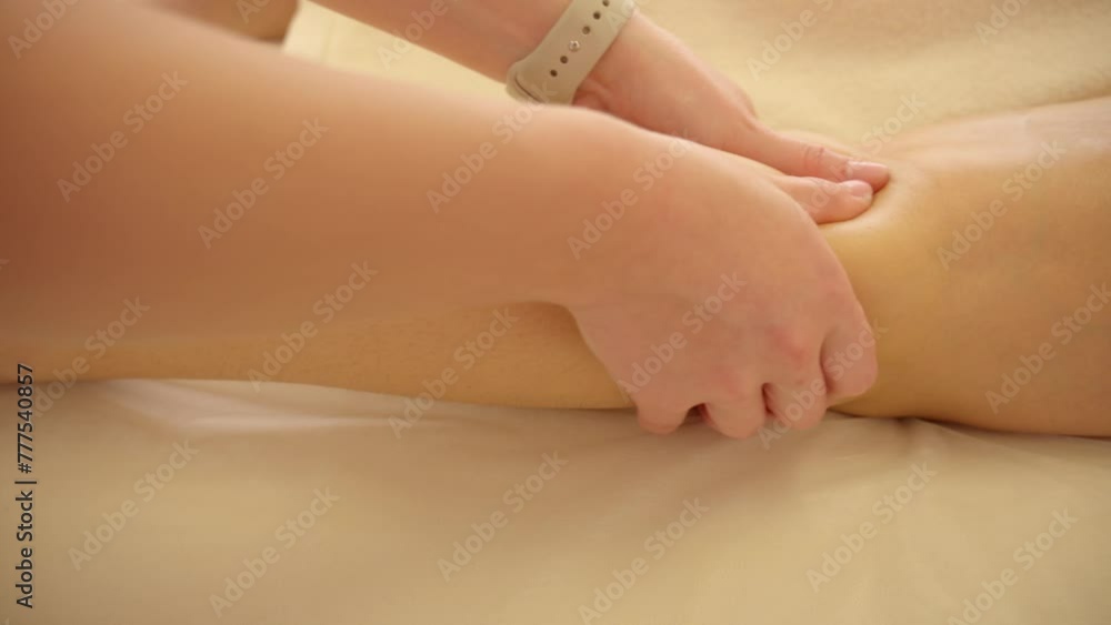 In the image, a therapist's hands are seen applying pressure to the calf muscle of a person lying on a massage table. In the image, a therapist's hands are seen applying pressure to the calf muscle of a person lying on a massage table.