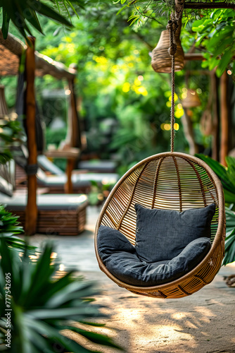 Gray cushion is hanging in wicker chair outside on patio surrounded by plants. © valentyn640