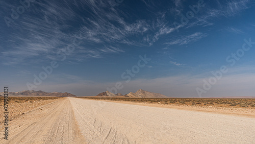 Straße im Namib-Naukluft Nationalpark, unendliche Weite, in Hintergrund Gebirge