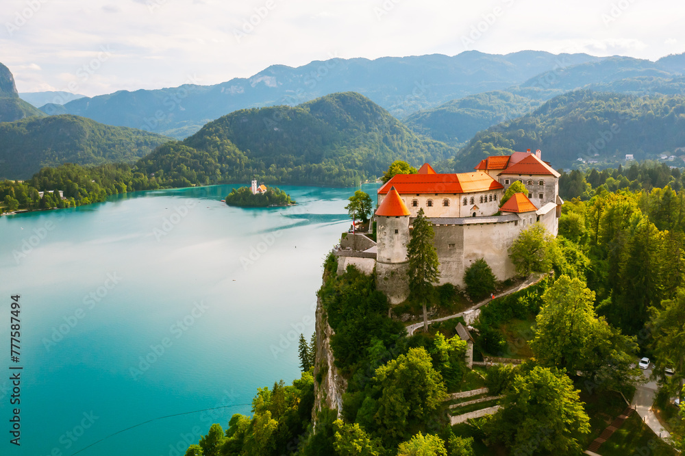Aerial view of mediaeval Bled castle on the cliff of the mountain under lake Bled with turquoise blue water in Slovenia