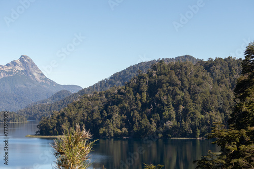 Fototapeta Naklejka Na Ścianę i Meble -  Calm and relaxing horizontal view of mountain range full of dense forests reflecting onto a lake's crystaline tranquil water wallpaper