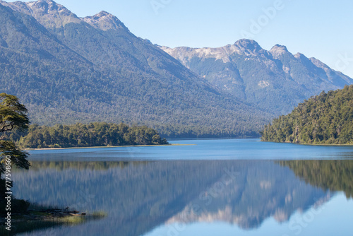 Calm and relaxing horizontal view of mountain range full of dense forests reflecting onto a lake's crystaline tranquil water wallpaper