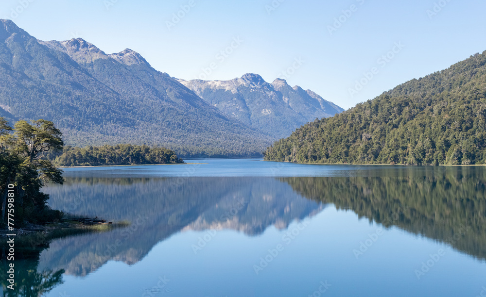 Calm and relaxing horizontal view of mountain range full of dense forests reflecting onto a lake's crystaline tranquil water wallpaper Calm and relaxing horizontal view of mountain range full of dense forests reflecting onto a lake's crystaline tranquil water wallpaper