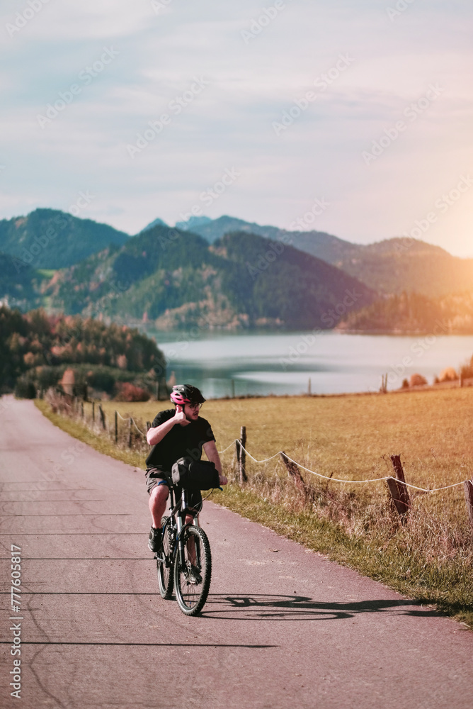 A cyclist riding a bike among the alpine mountains. Concept of the active healthy lifestyle. Mountain road with an alpine lake in the background. Vacation with nature. Concept of Human Recreation.