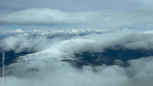 Snowed mountains covered with some flufly clouds. Guadalajara, Spain. Pilot POV. Forward aerial shot from an airplane cockpit. 4K. photo