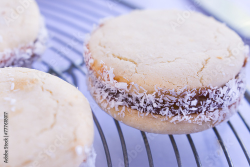 Close up of gluten free cornstarch cookies filled with dulce de Leche and grated coconuts on metal cooling rack